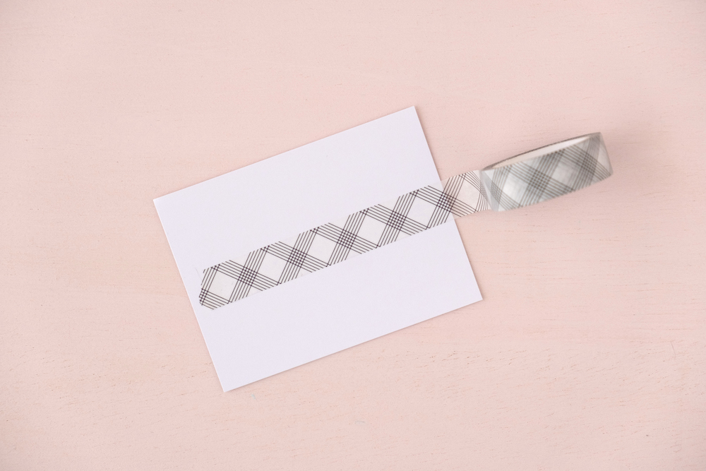 Fita decorativa autocolante com padrão xadrez cinzento e branco sobre papel branco