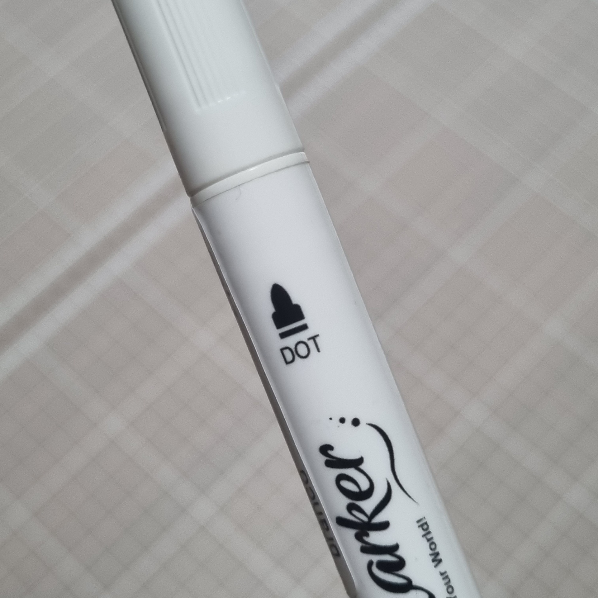 Aplicador branco com texto DOT e parte de sparkler em fundo cinza xadrez