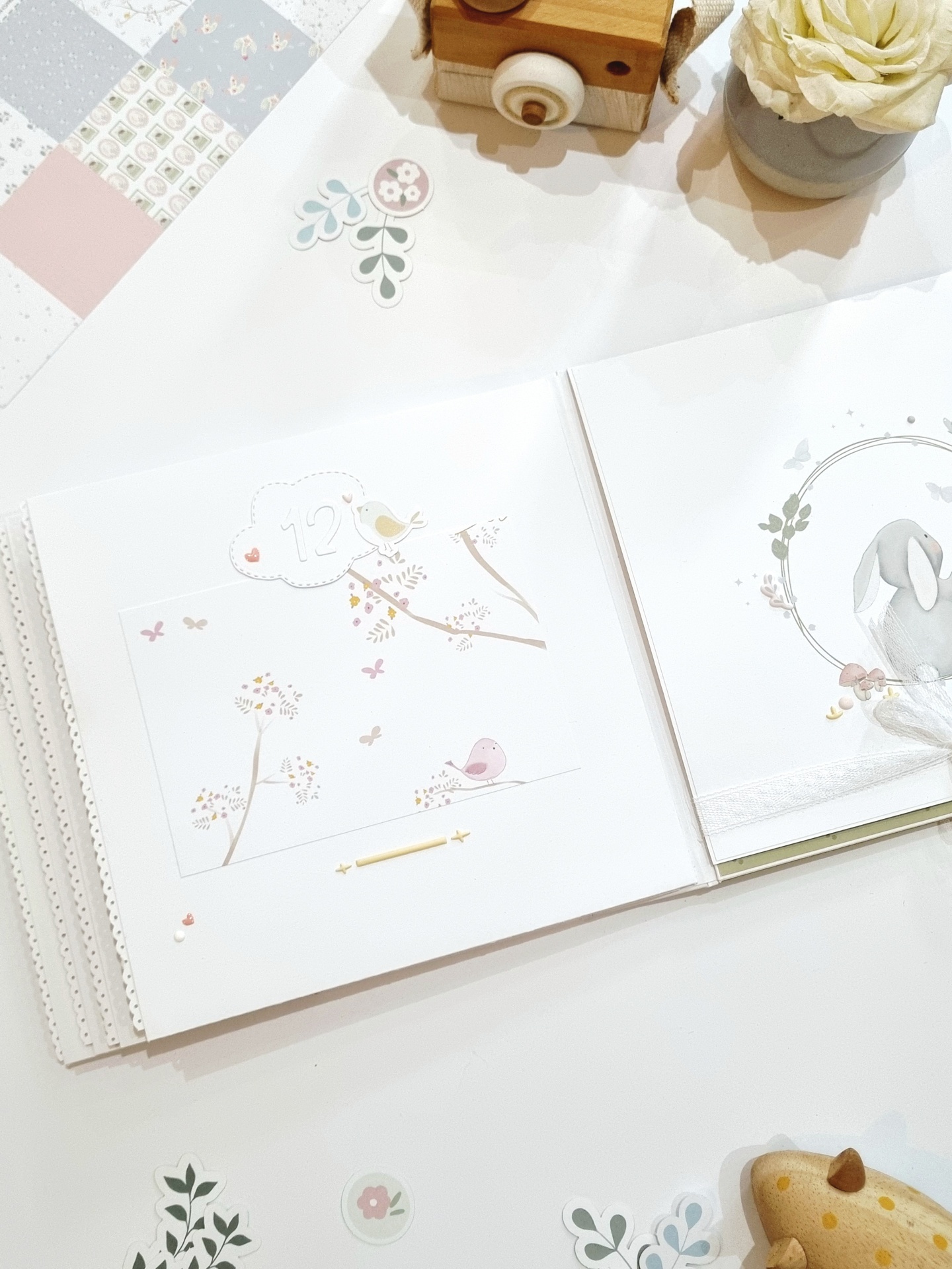 Livro de páginas com ilustrações de pássaros e coelho em tons pastéis