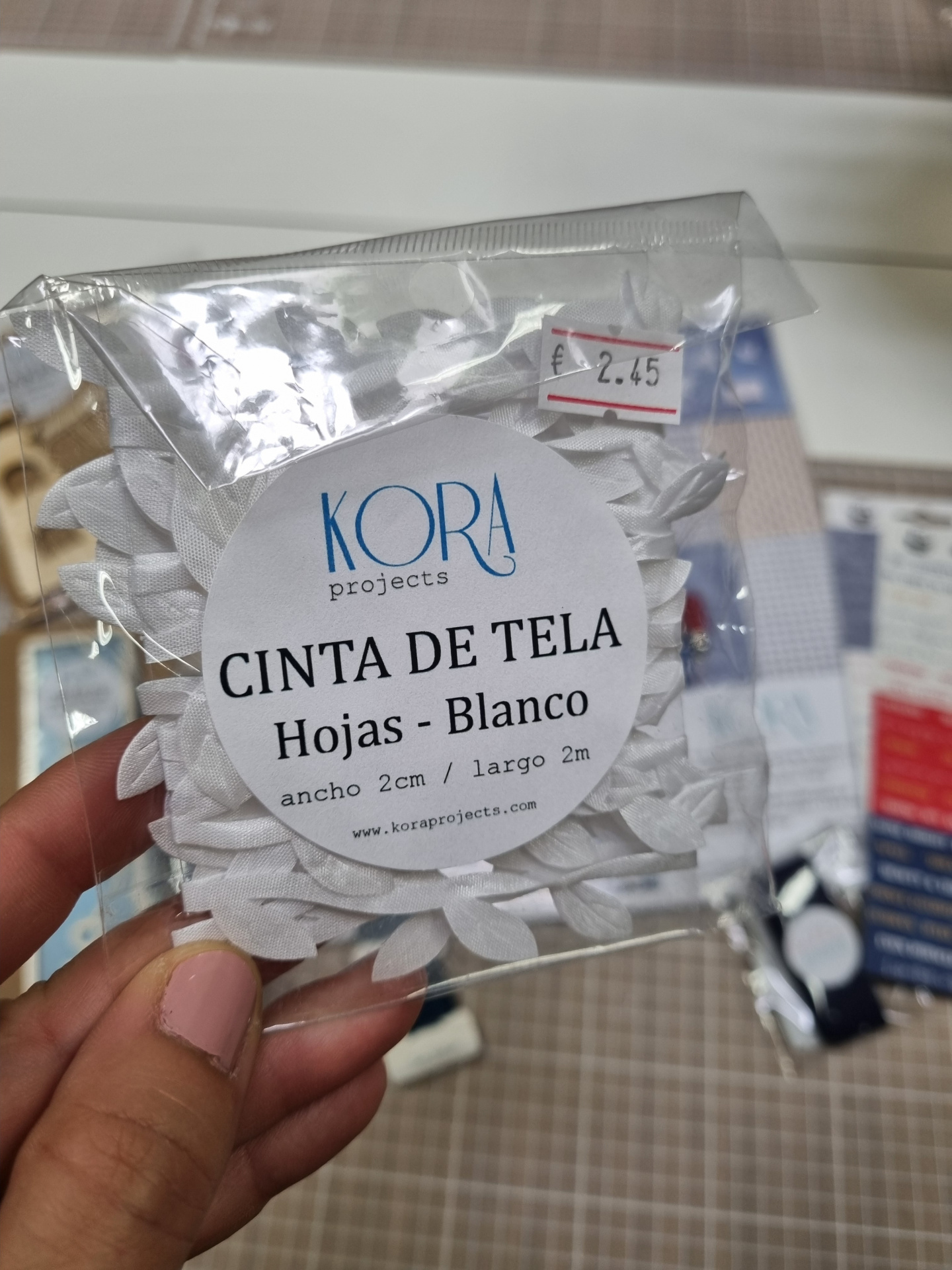 Pacote de fita de tecido branco com padrão de folhas, etiqueta visível e preço