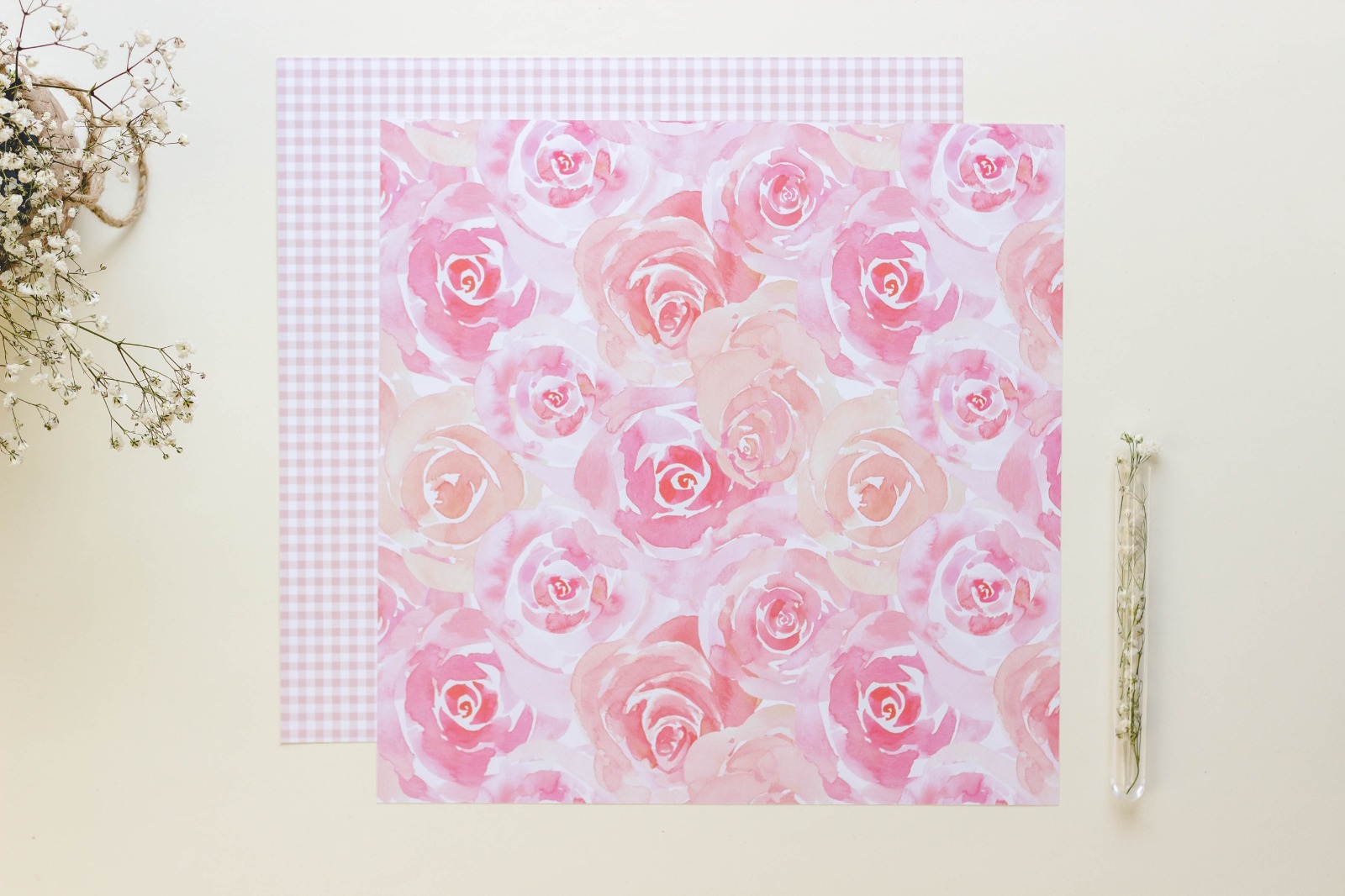 Dois papéis decorativos rosas com flores e padrão xadrez, ramo de flores e tubo com pó