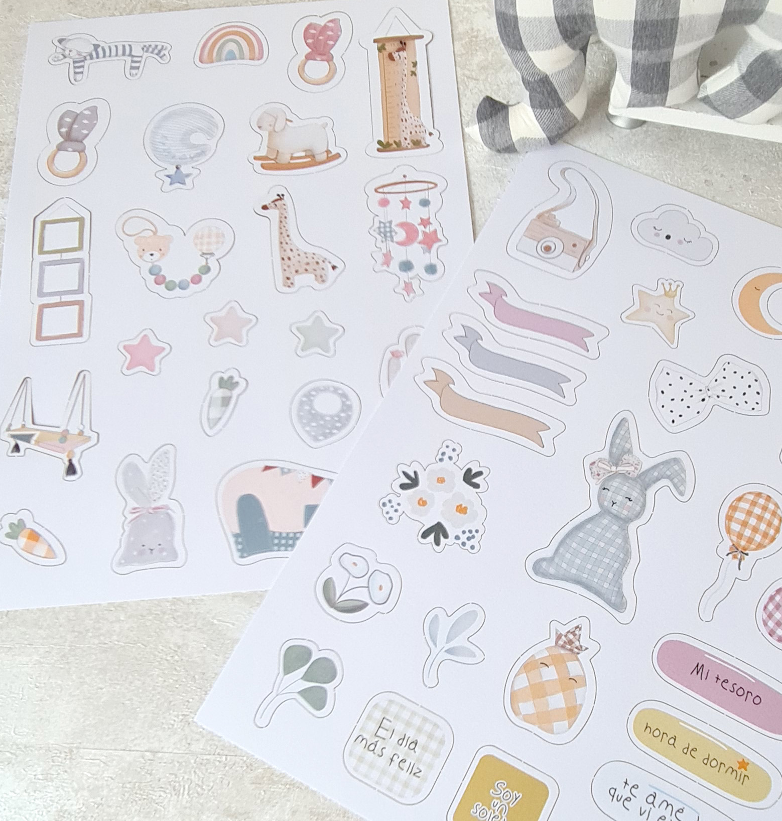 Autocolantes infantis com desenhos e frases em espanhol, cores suaves, superfície clara, manta xadrez cinzenta