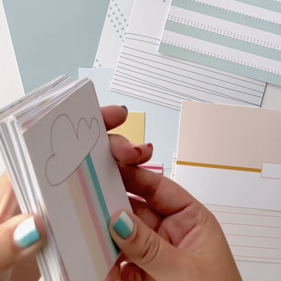 Cartões de papel com desenhos minimalistas em tons pastel e folhas pautadas ao fundo