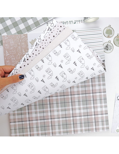 Papéis de embrulho decorativos com vários padrões e cores suaves, segurados por uma mão