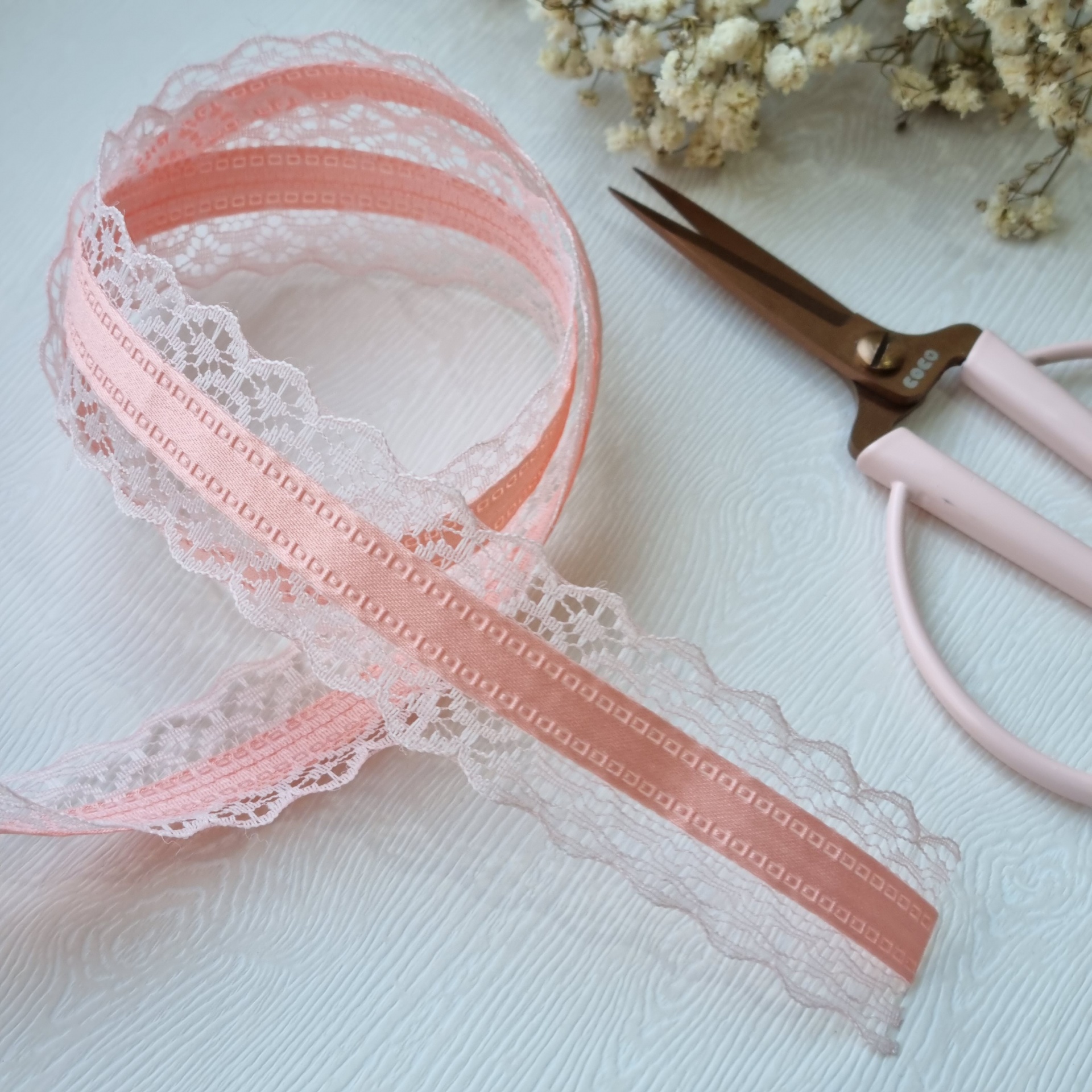 Fita decorativa cor-de-rosa com bordado rendado branco, tesoura rosa e flores secas
