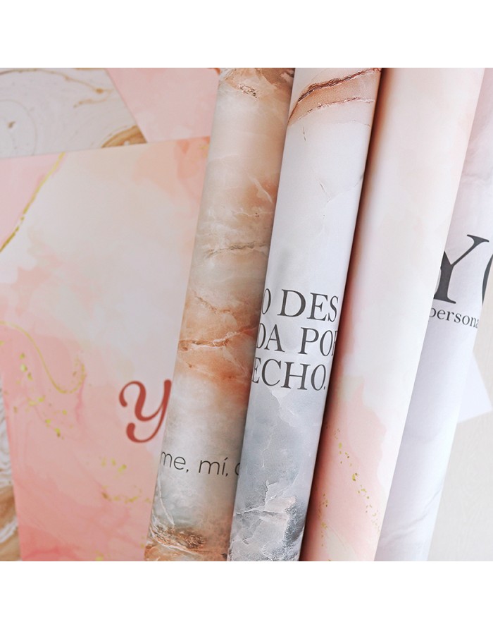 Rolos de papel decorativo com padrões marmorizados e texto parcial em tons neutros