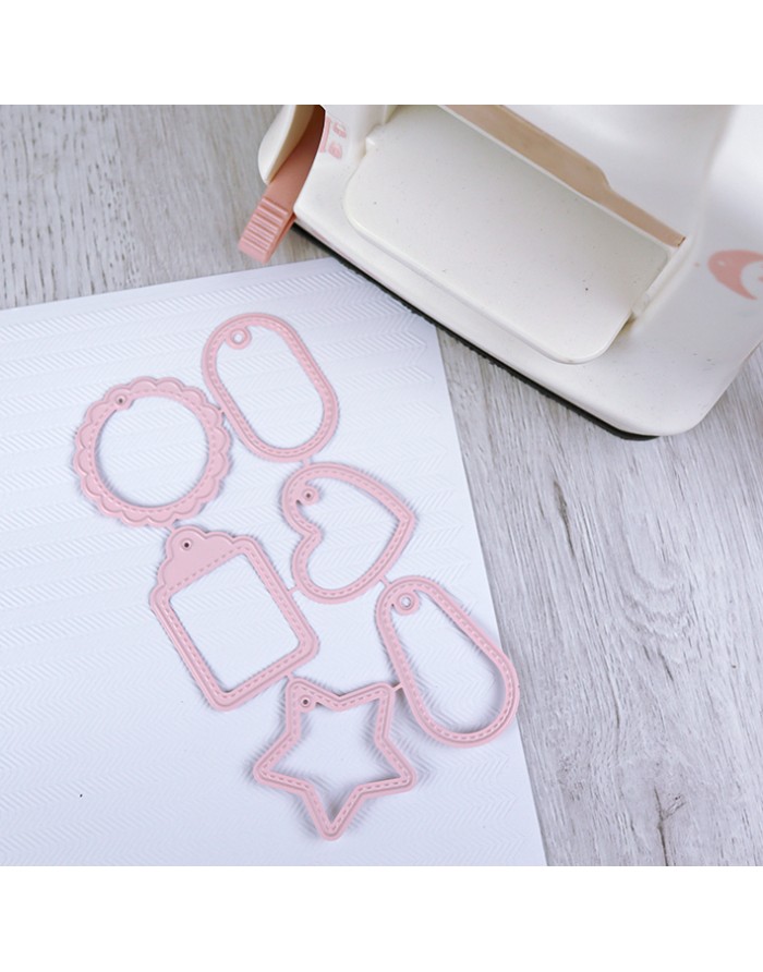 Conjunto de moldes metálicos rosa para recortes e máquina de corte branca em fundo claro