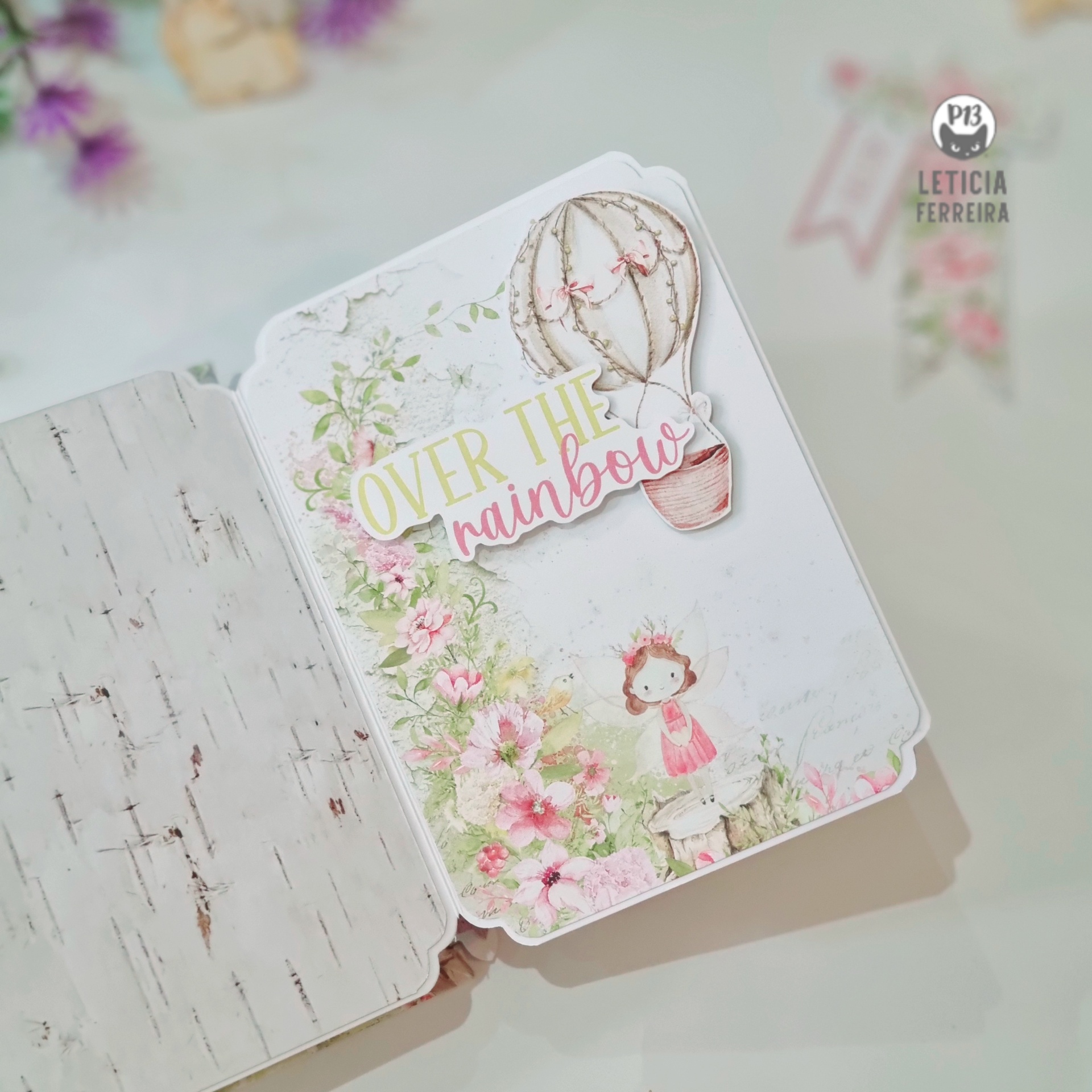 Caderno aberto com ilustração infantil, flores e balão com texto em inglês.