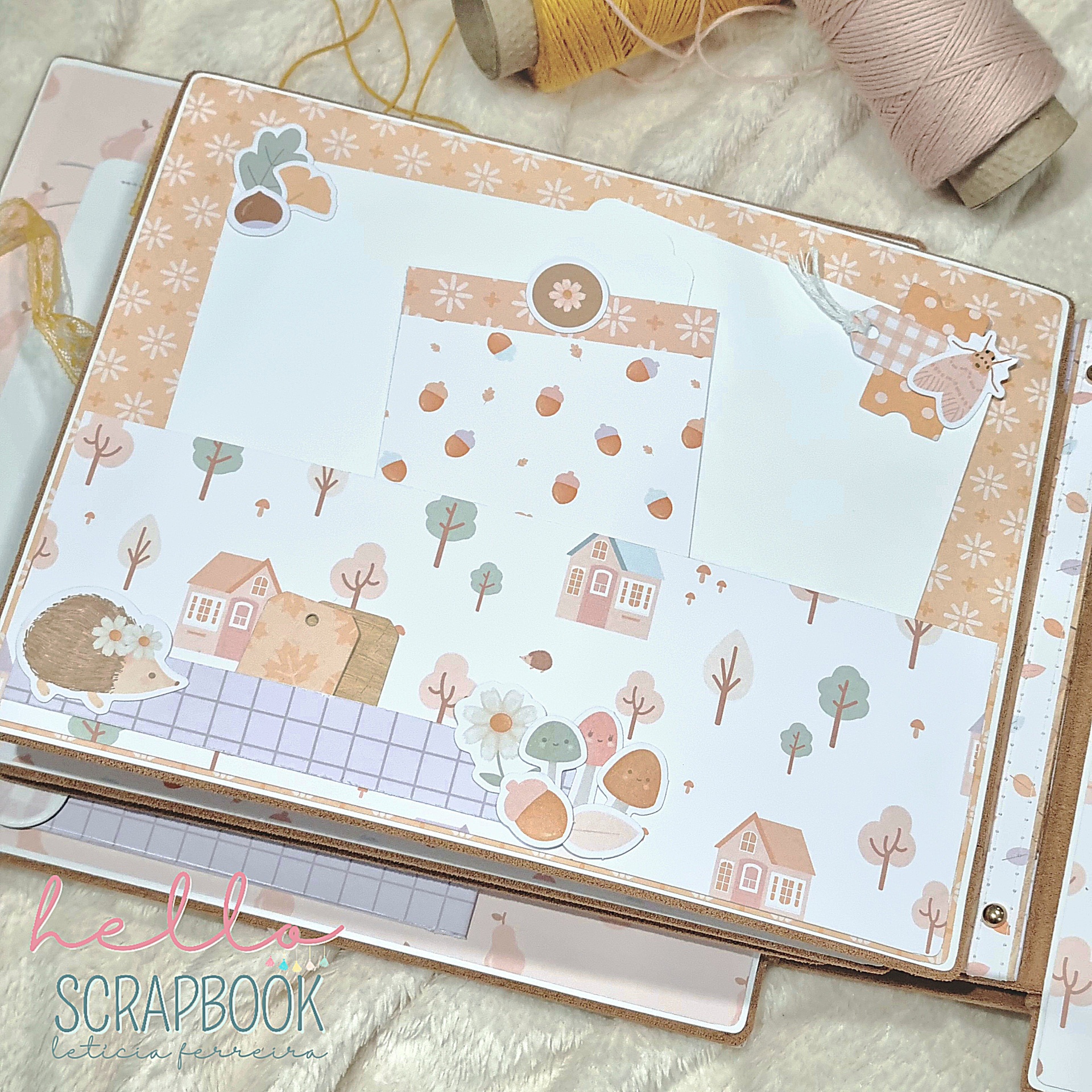 Álbum de scrapbook decorado com desenhos de casas, árvores, ouriço e cogumelos