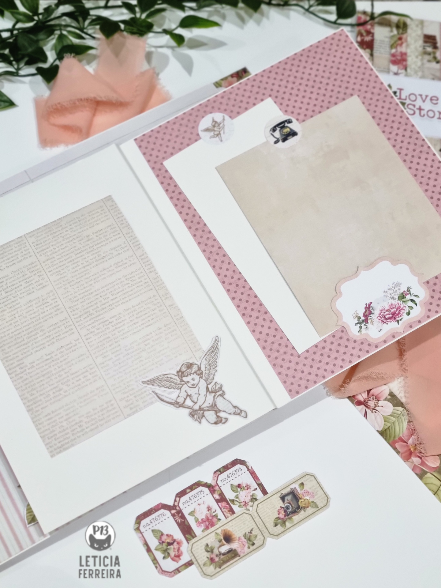 Caderno de scrapbook aberto com páginas decorativas e recortes florais num ambiente claro com tecido rosa.