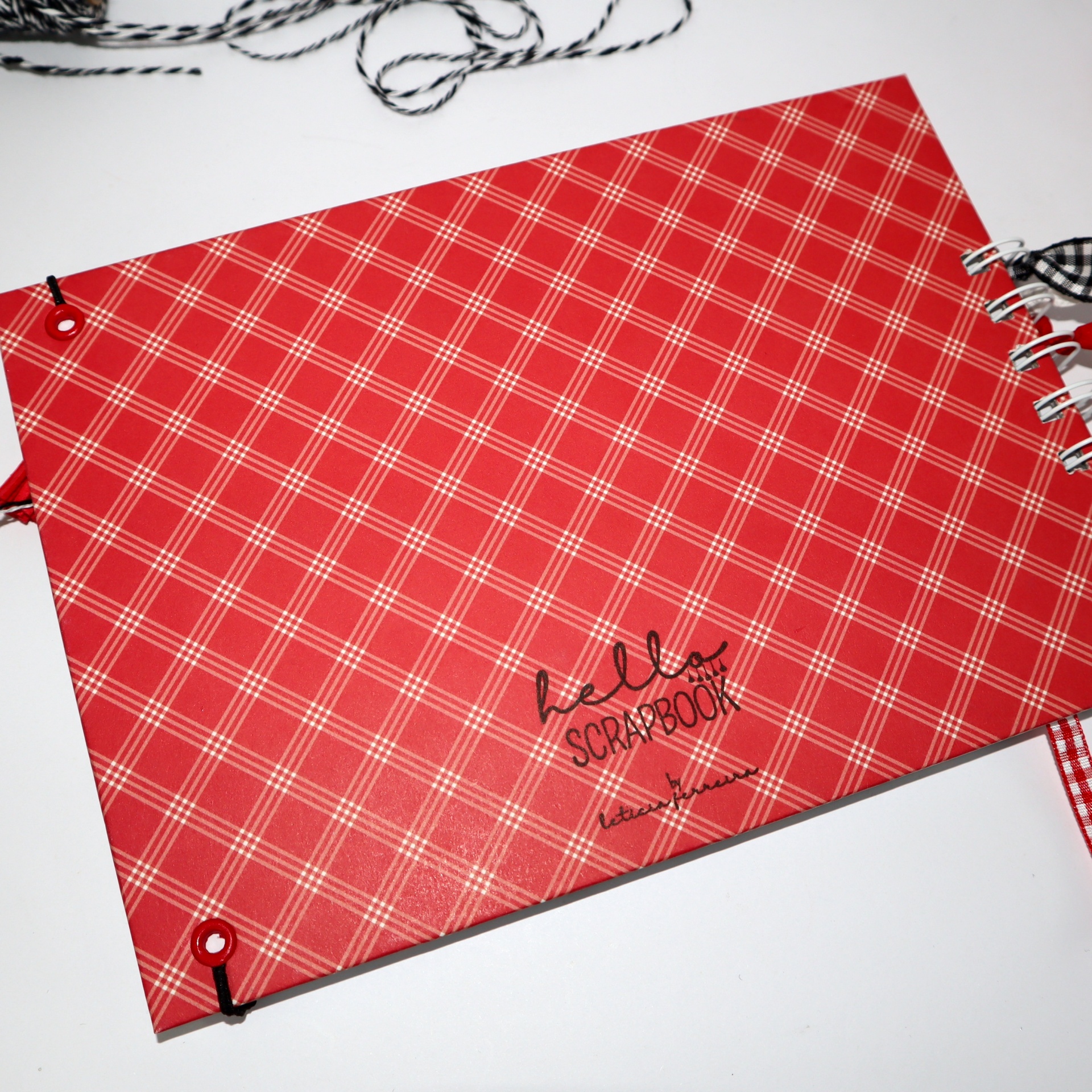 Álbum scrapbook vermelho com padrão de linhas cruzadas e texto no centro