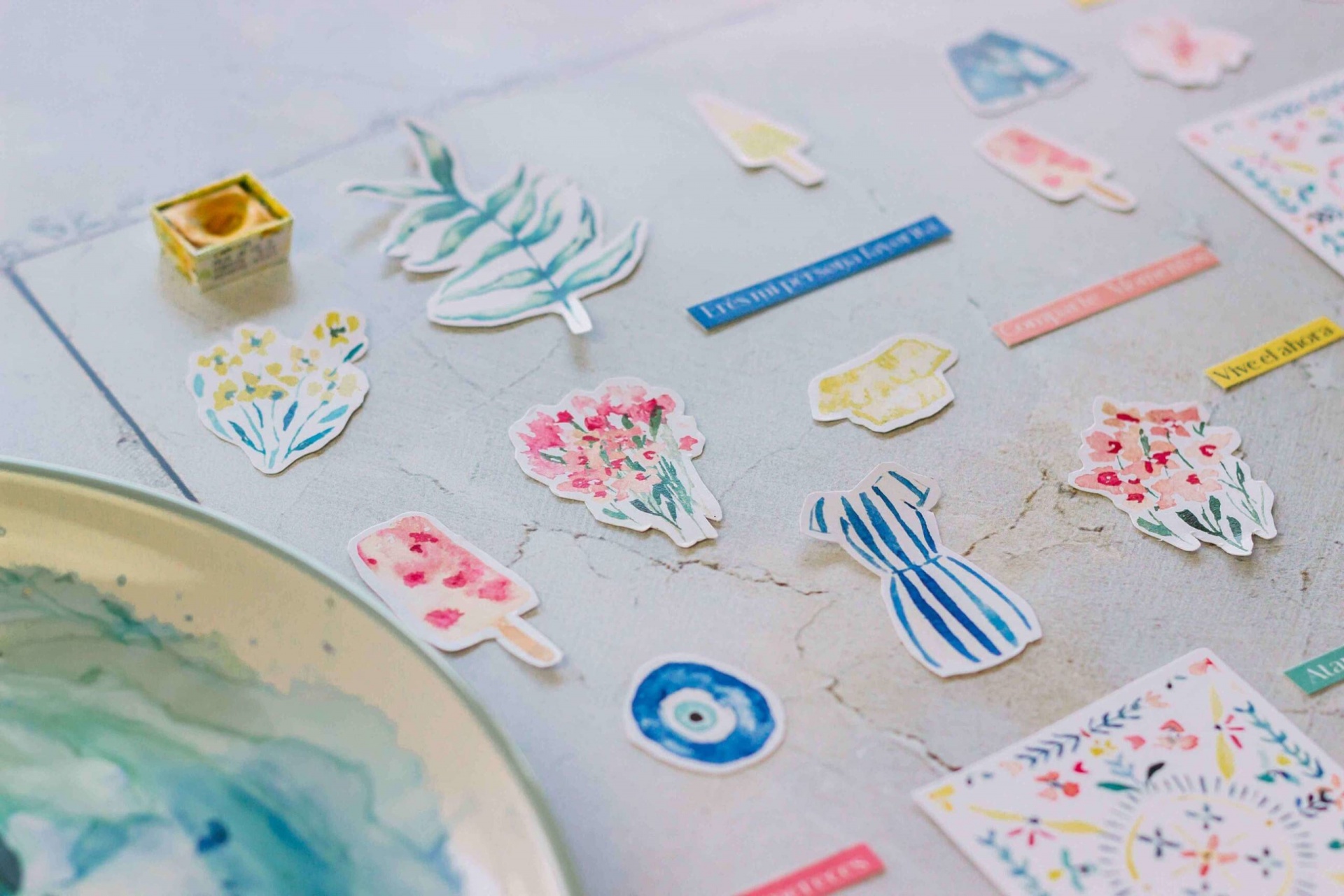 Autocolantes coloridos com motivos naturais e objetos sobre superfície clara rachada