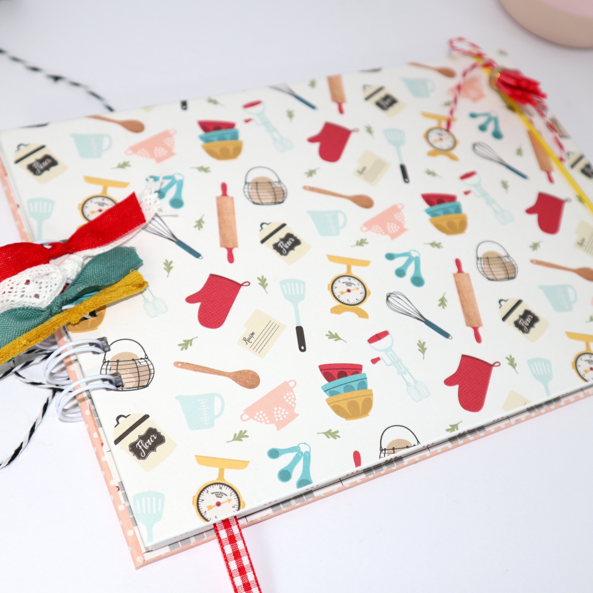 Caderno com capa decorada por ilustrações de utensílios de cozinha e fitas coloridas
