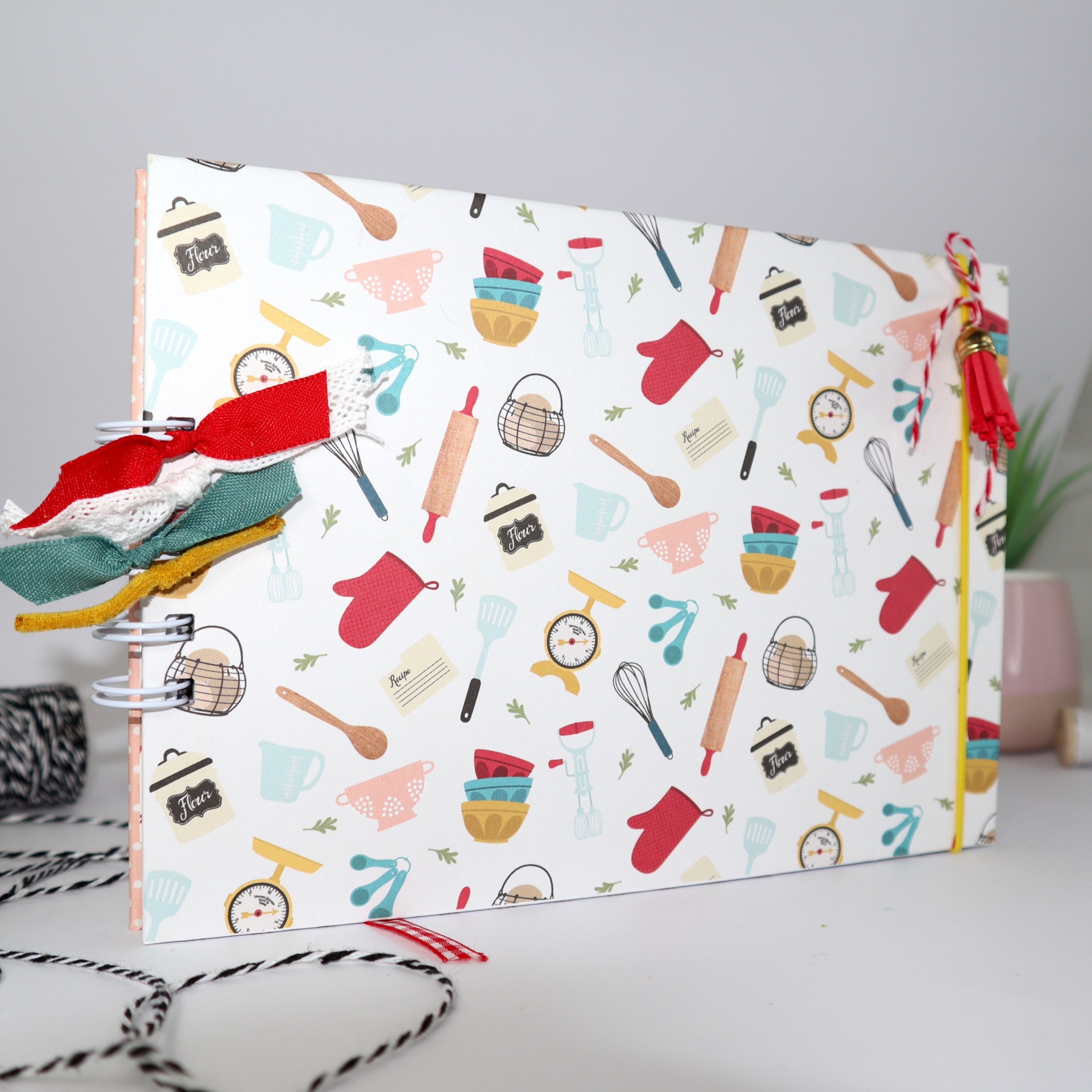 Caderno com capa decorada com padrão colorido de utensílios de cozinha e fitas coloridas no espiral