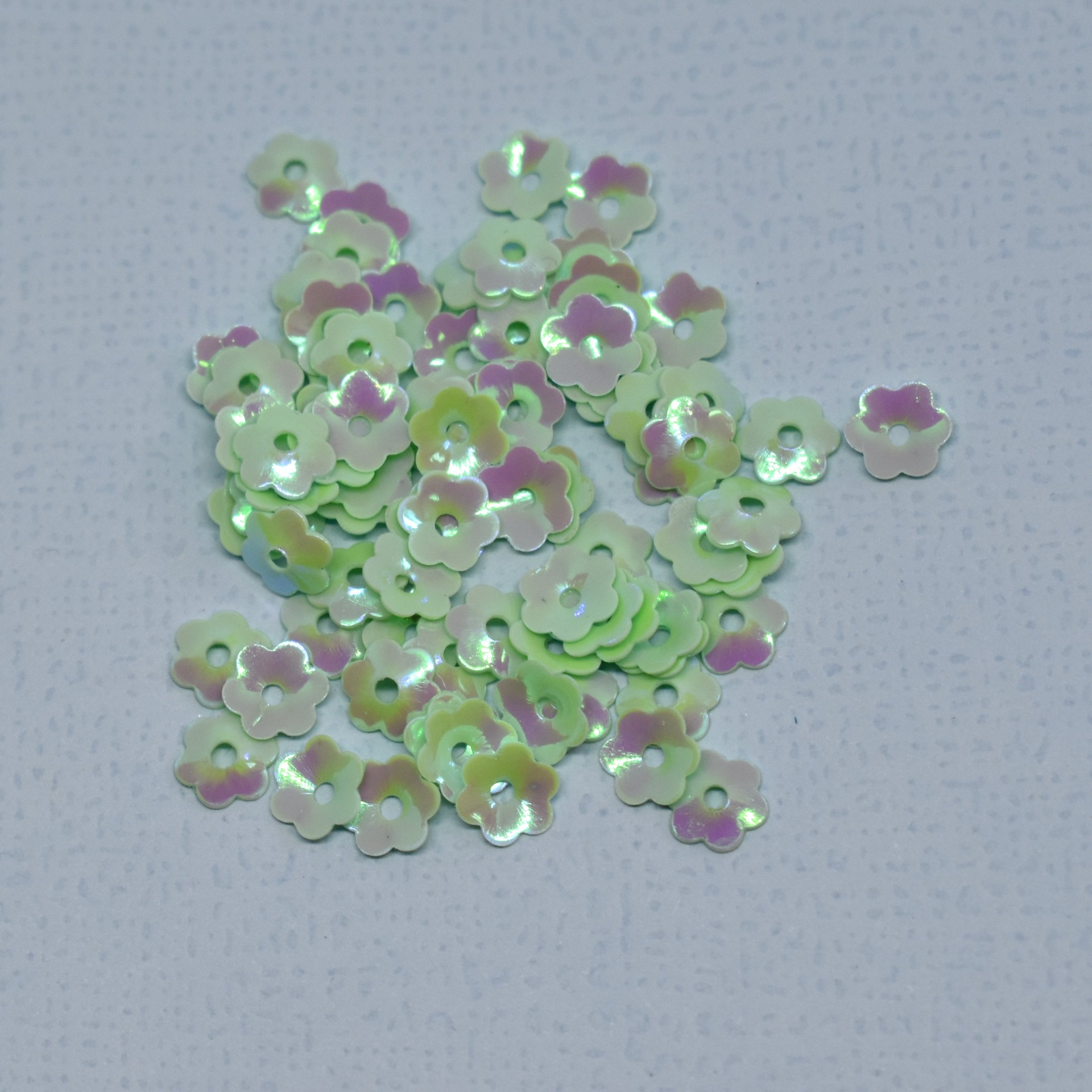 Lantejoulas flores irisadas amarelo, verde e lilás em fundo branco