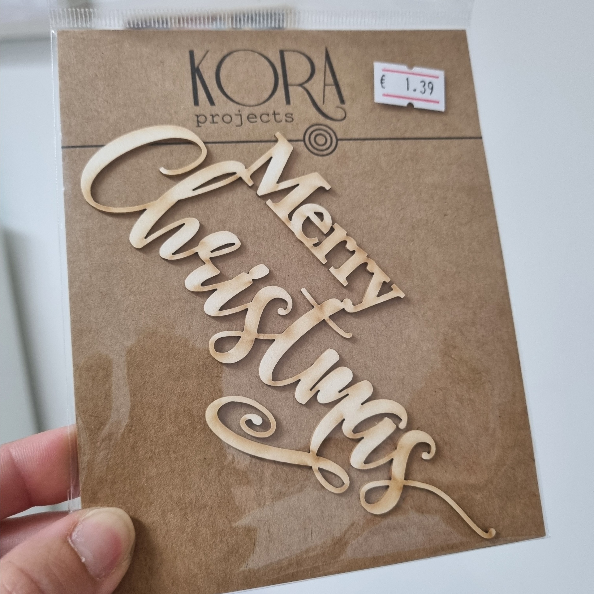 Letra em madeira clara com a frase Merry Christmas na embalagem