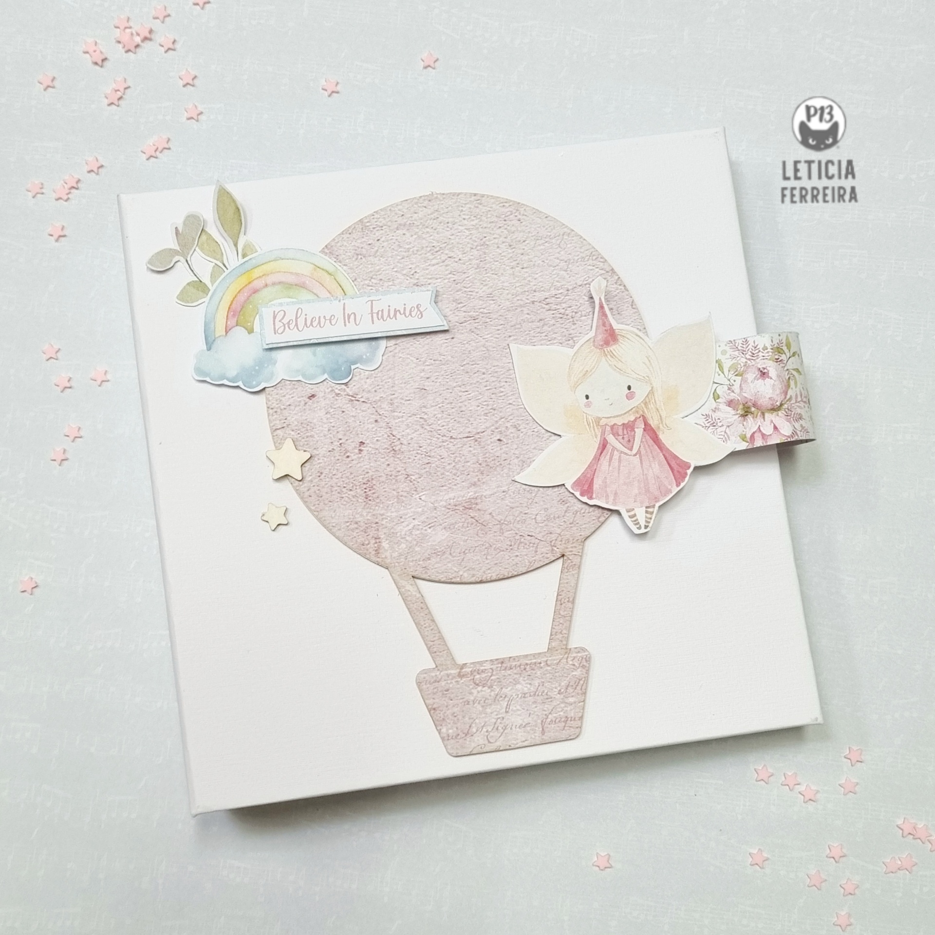 Álbum branco com decoração de balão de ar quente, fada e texto em tons pastel