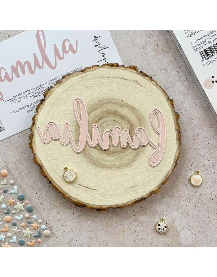 Placa decorativa de madeira redonda com palavra 'família' em rosa claro e pequenos itens decorativos ao redor