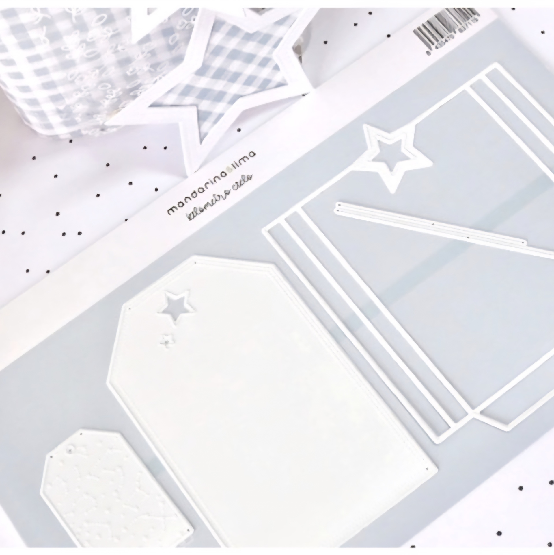 moldes metálicos brancos com forma de estrelas e etiquetas em fundo cinzento e tecido de fundo