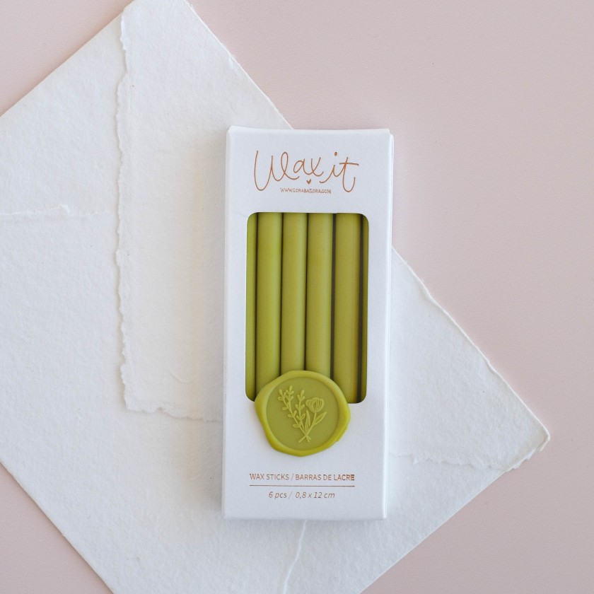 Conjunto de velas verdes em embalagem branca com texto 'Wax it' e selo verde decorativo