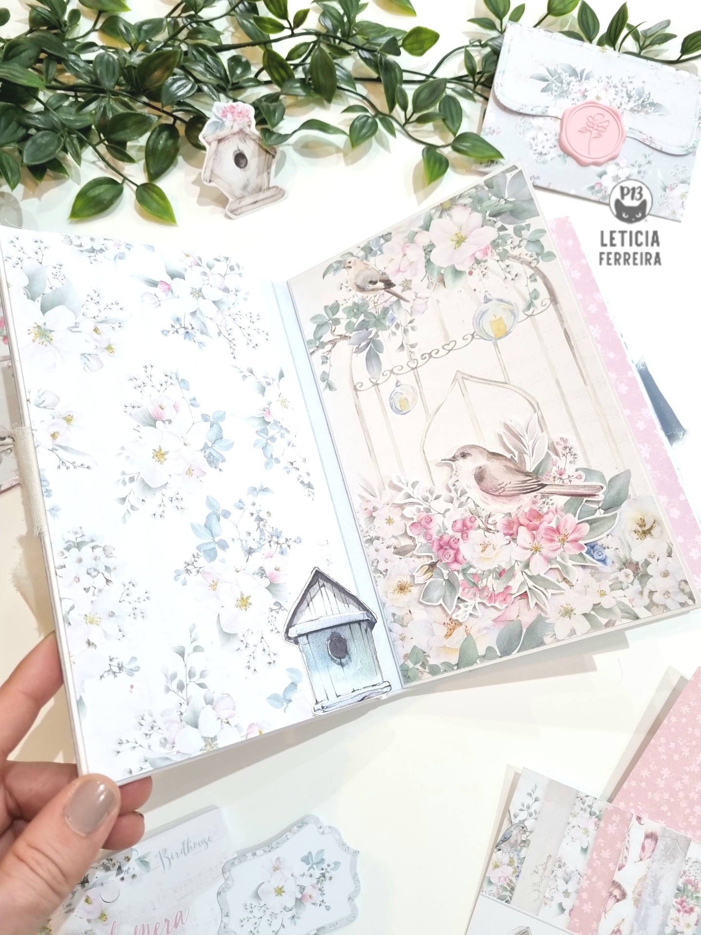 Livro decorativo aberto com flores e pássaros, cores pastel e elementos florais