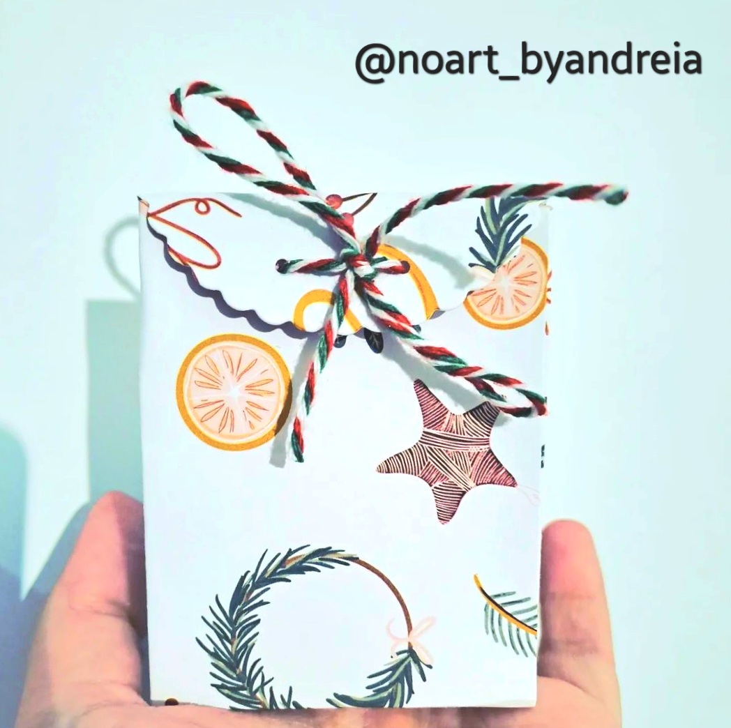 Presente embrulhado com papel decorado e laço tricolor, mãos seguram o presente