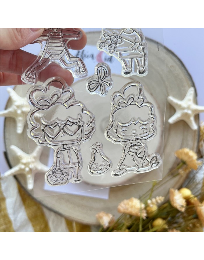 Conjunto de carimbos transparentes com personagens infantis e elementos decorativos em fundo com estrelas-do-mar e flores
