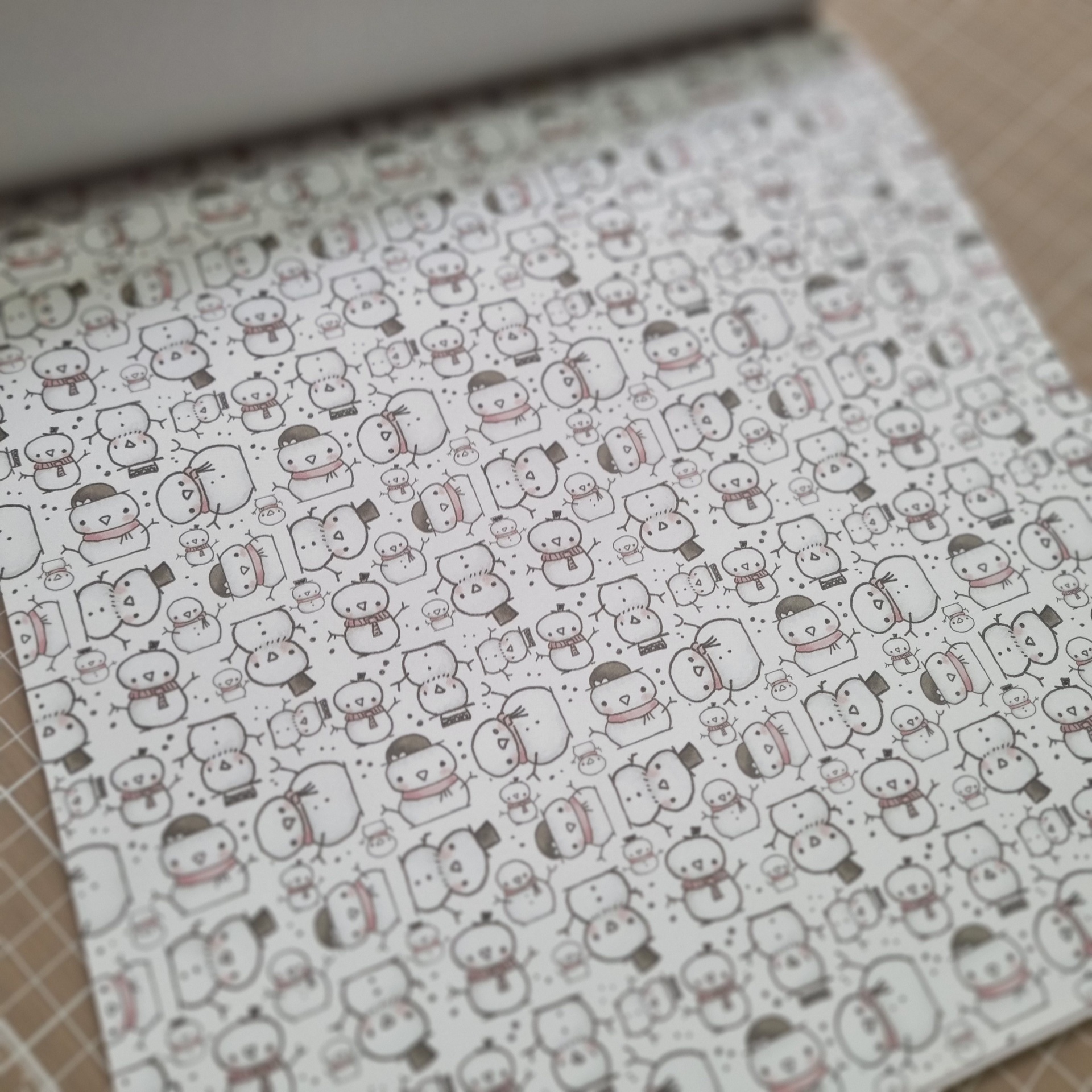 Papel de embrulho com bonecos de neve desenhados num padrão repetido