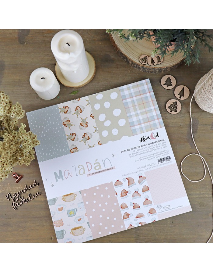 Folhas de scrapbook com padrões variados em tons pastel e elementos decorativos de Natal numa mesa de madeira