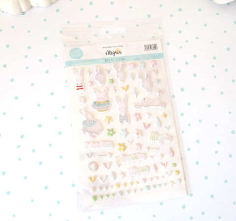 Folha de autocolantes de coelhos rosa claro com detalhes amarelos, verdes e azuis sobre fundo branco com pontos azuis