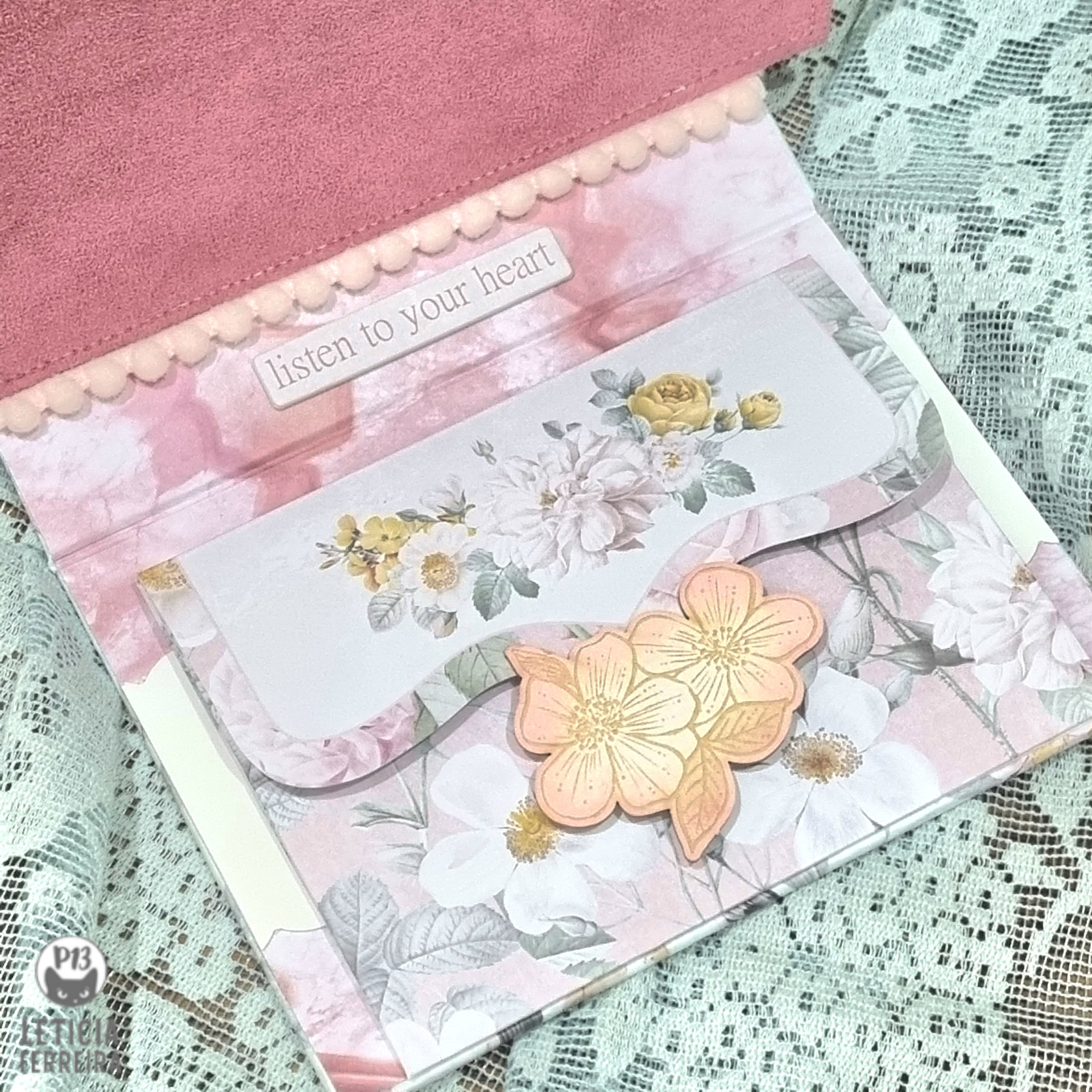 Carteira rosa com padrão floral e texto 'listen to your heart' sobre renda bege