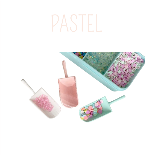 Três pás transparentes com pequenos objetos coloridos e caixa de confetes pastéis