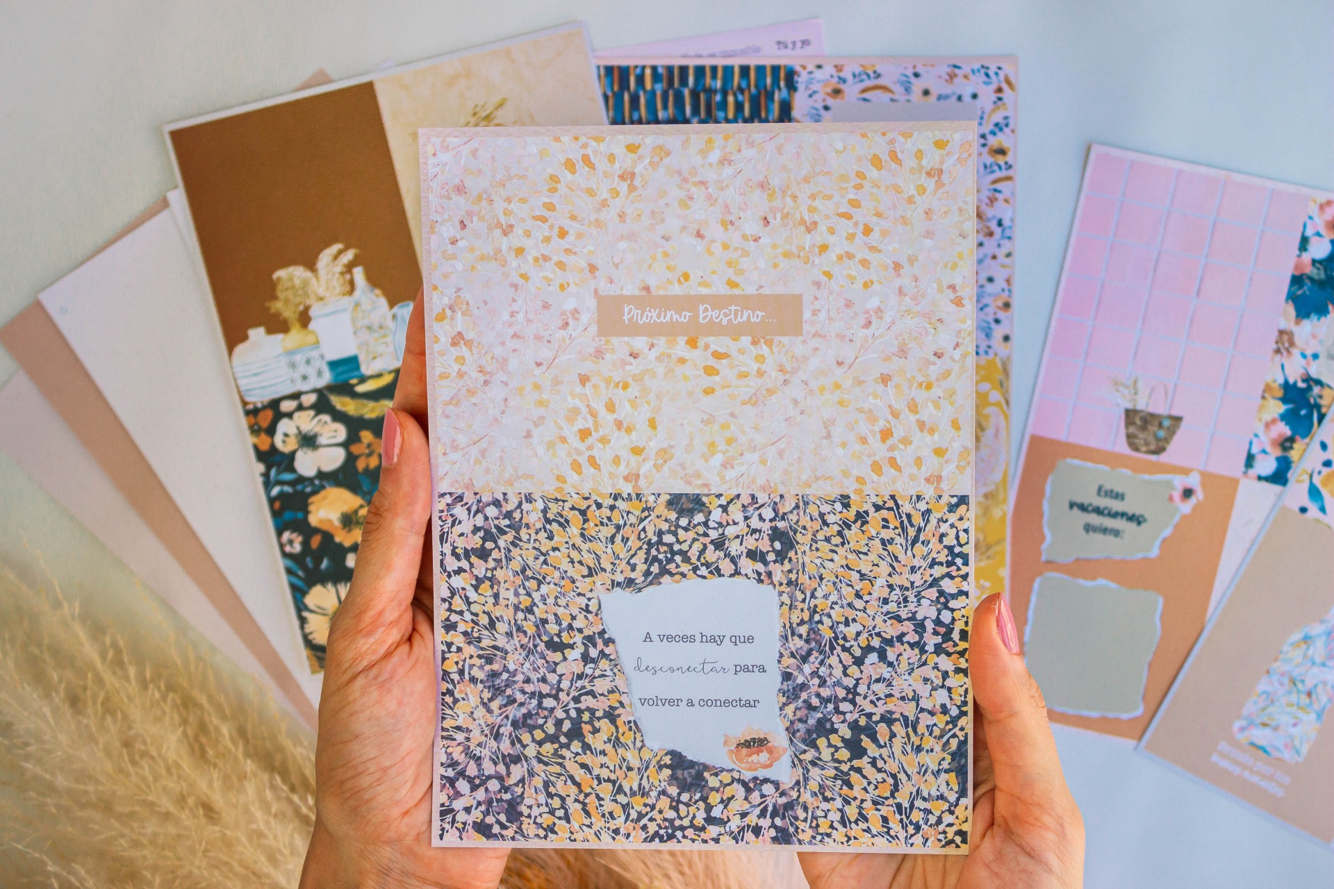 Caderno com capa floral segura por mãos, outros cadernos ao fundo
