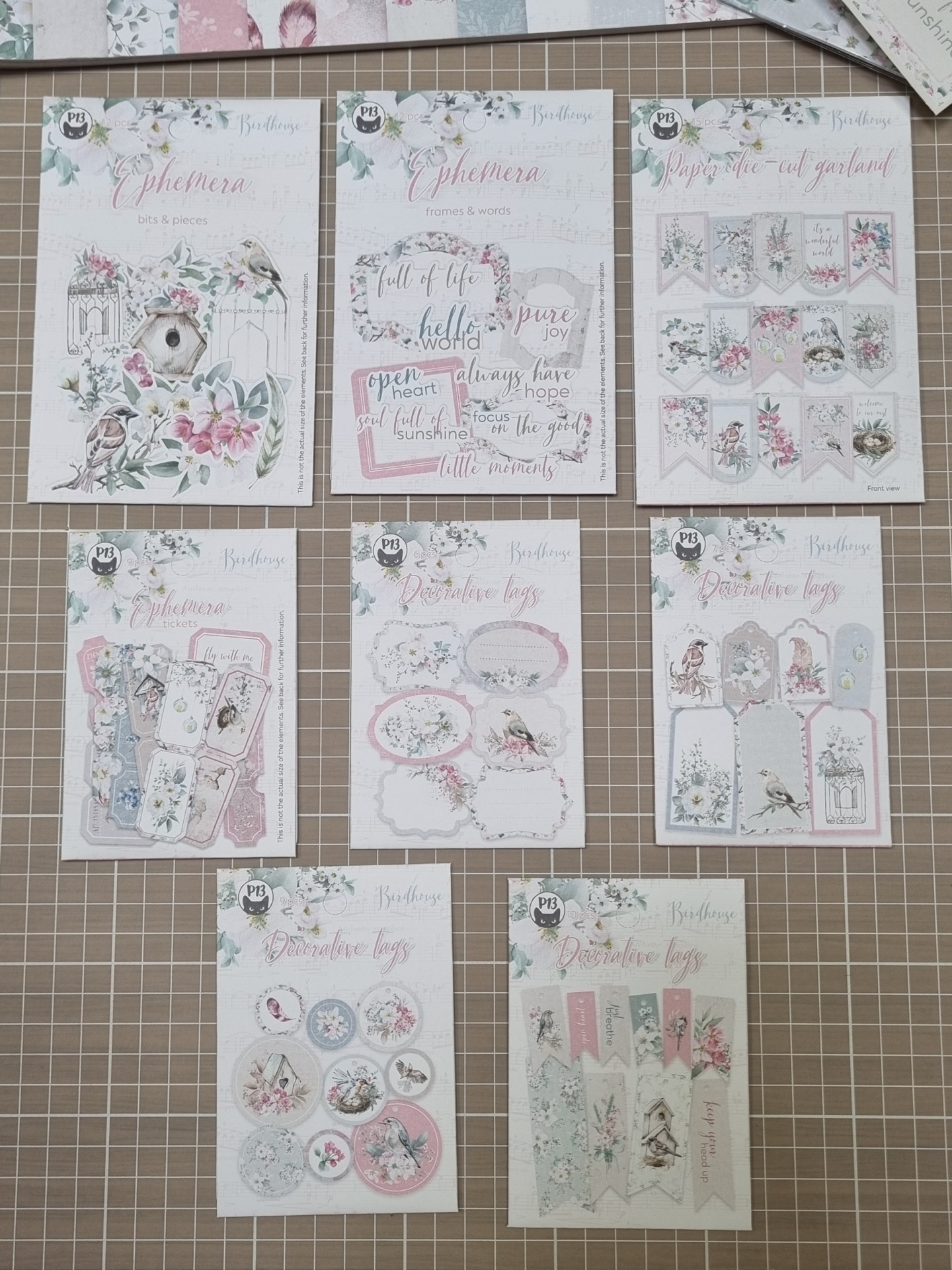 Papéis recortados decorativos com temas de pássaros e flores em tons pastel