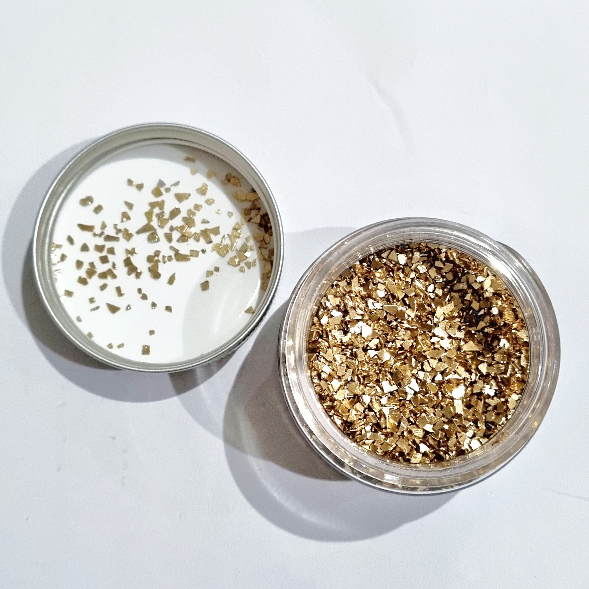 Frasco aberto com purpurina dourada e tampa metálica ao lado
