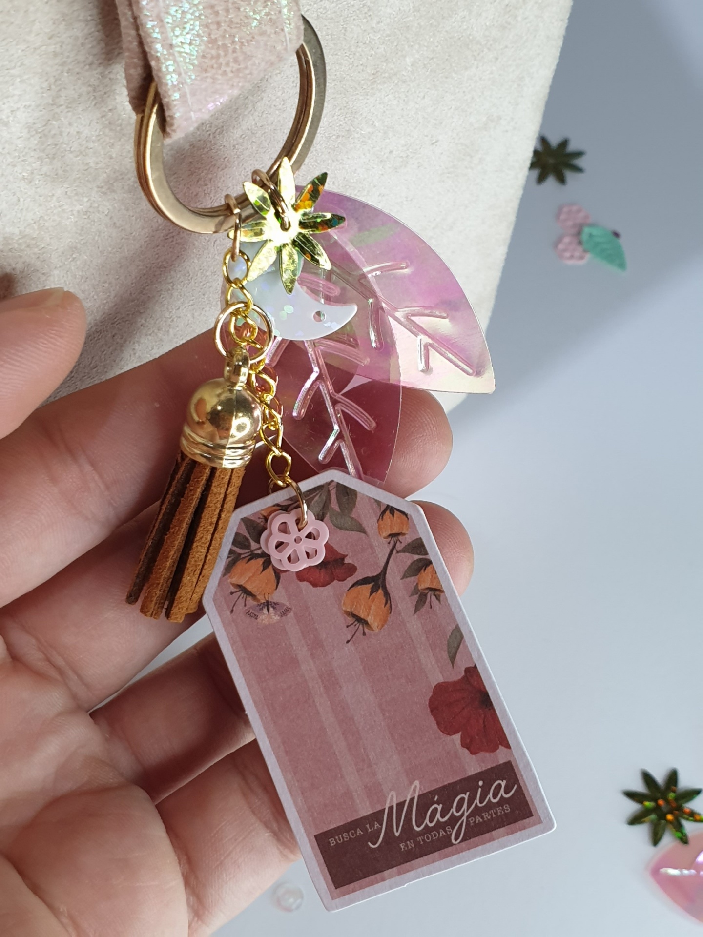 Chaveiro com folha translúcida rosa, franjas castanhas e placa decorativa com texto