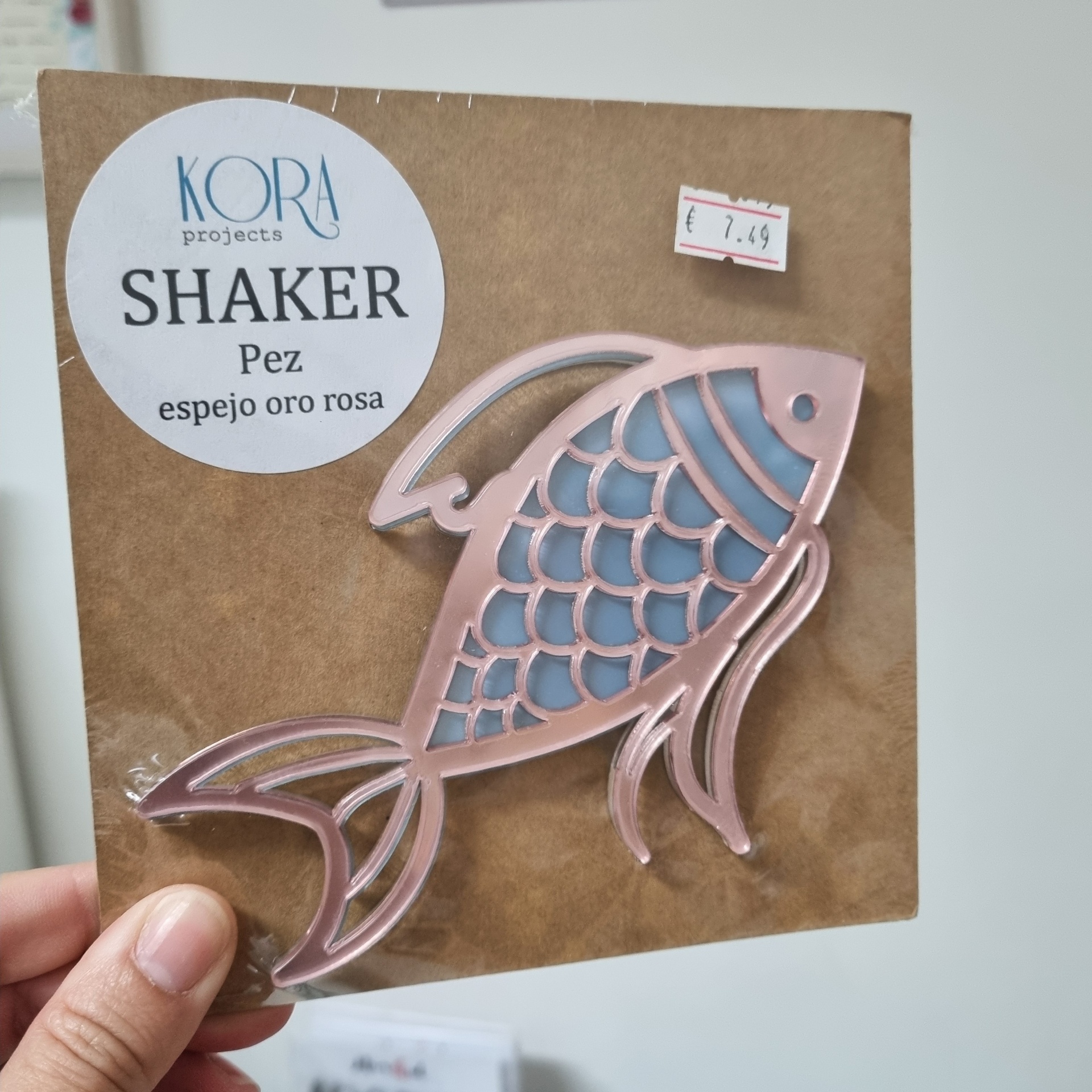 Espelho decorativo em forma de peixe rosa e azul em embalagem de cartão com etiqueta KORA e preço