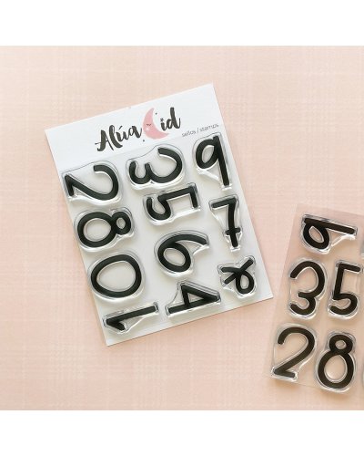 Selos de números em silicone preto da Alúa Cid sobre fundo rosa claro