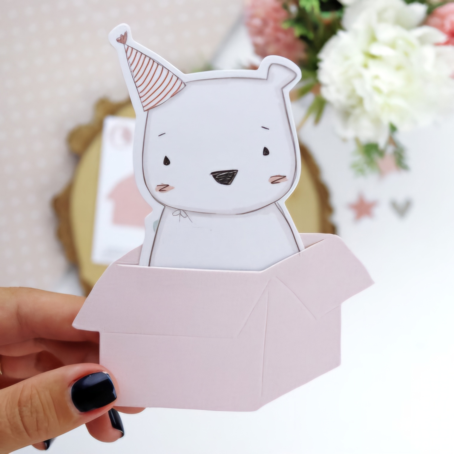 Figura de papel de urso branco com chapéu de festa numa caixa rosa