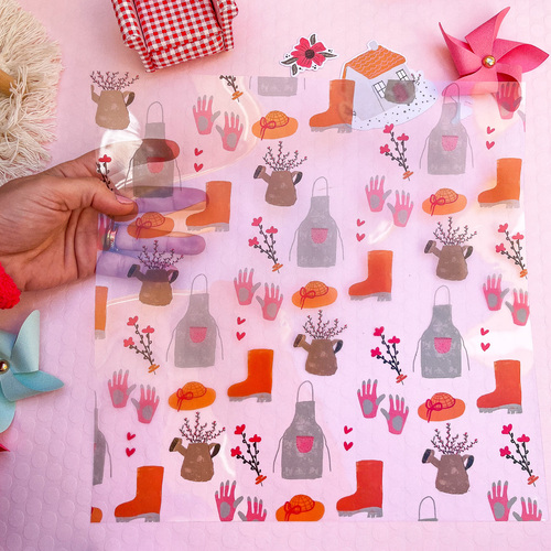 Saco plástico transparente com padrão colorido de elementos de jardinagem sobre fundo rosa