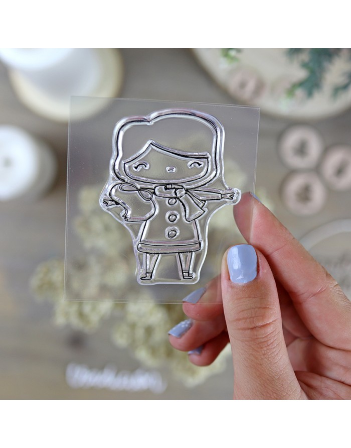 Carimbo de silicone transparente com desenho de boneca e unha pintada de azul claro segurando o carimbo