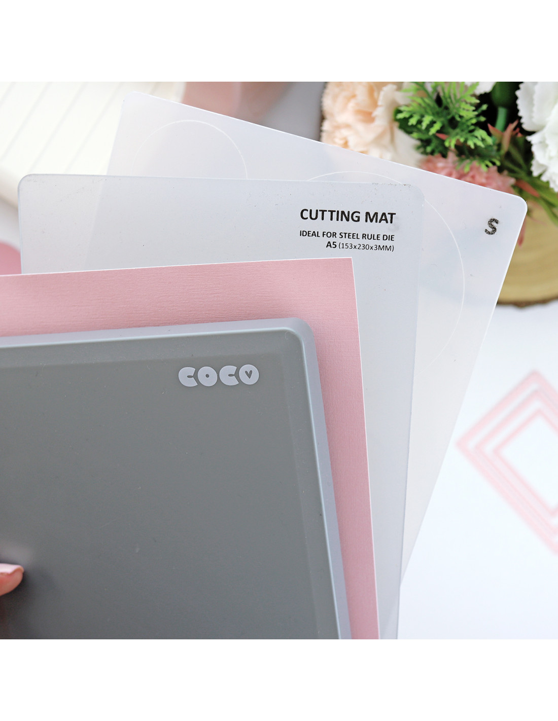 Três tapetes de corte sobrepostos em cores transparente, rosa e cinzento