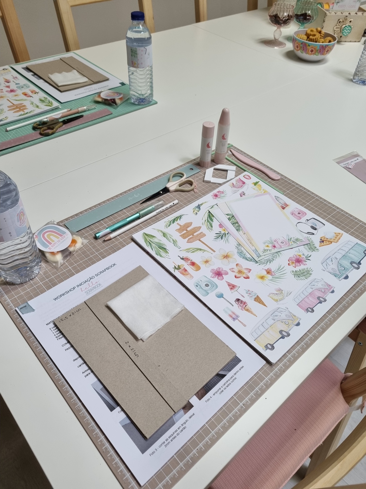 Mesa com materiais de papelaria para trabalhos manuais, incluindo folhas, tesouras, cola e régua.