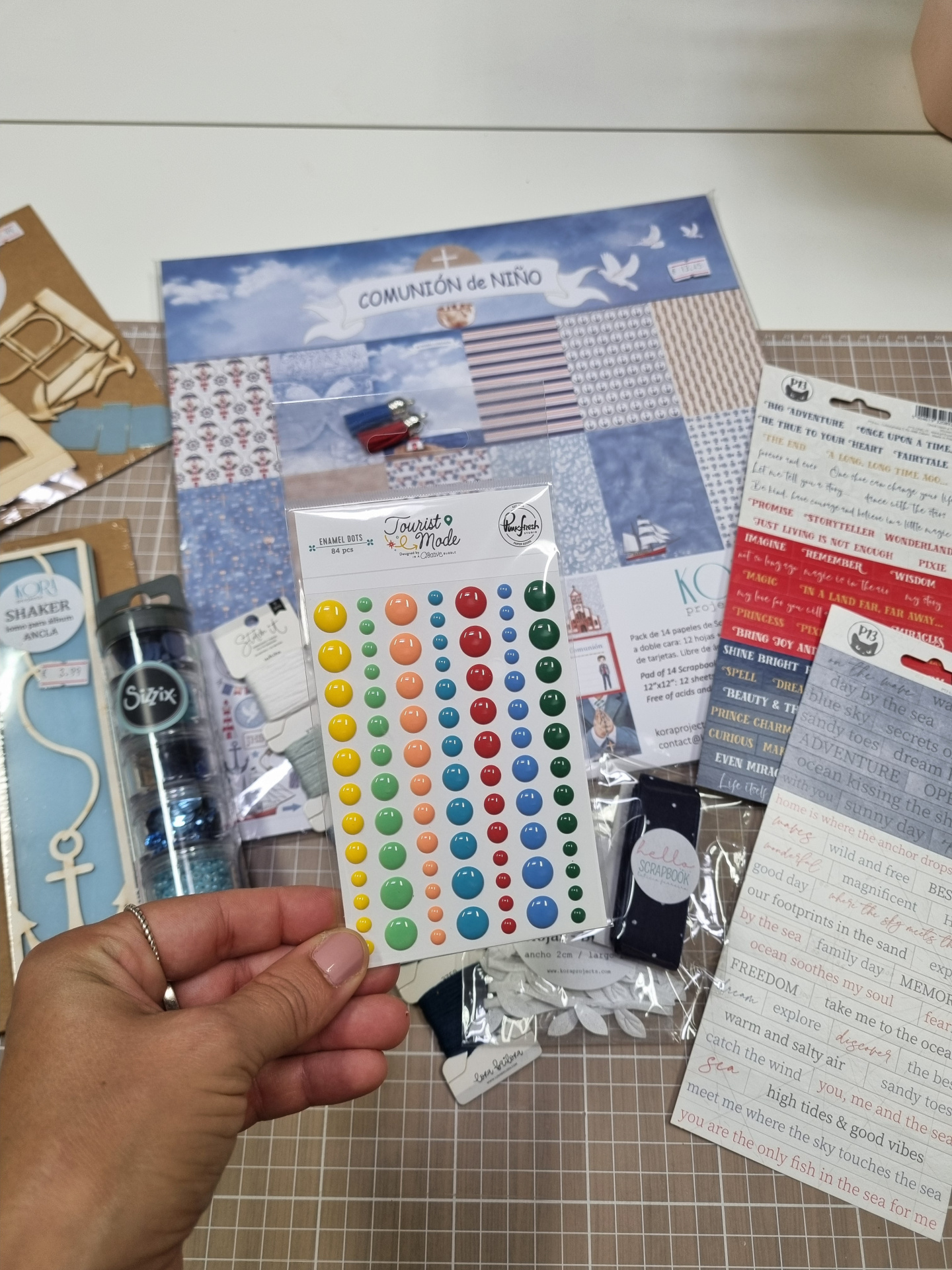 Pinos esmaltados coloridos para scrapbooking e papéis decorativos temáticos em mesa clara.