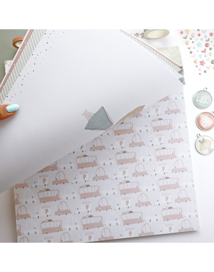 Papel decorativo com padrão de carros cor-de-rosa sendo levantado por uma mão sobre uma mesa com objetos de artesanato