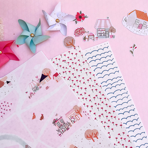 Papéis decorativos coloridos e moinhos de papel sobre fundo rosa.