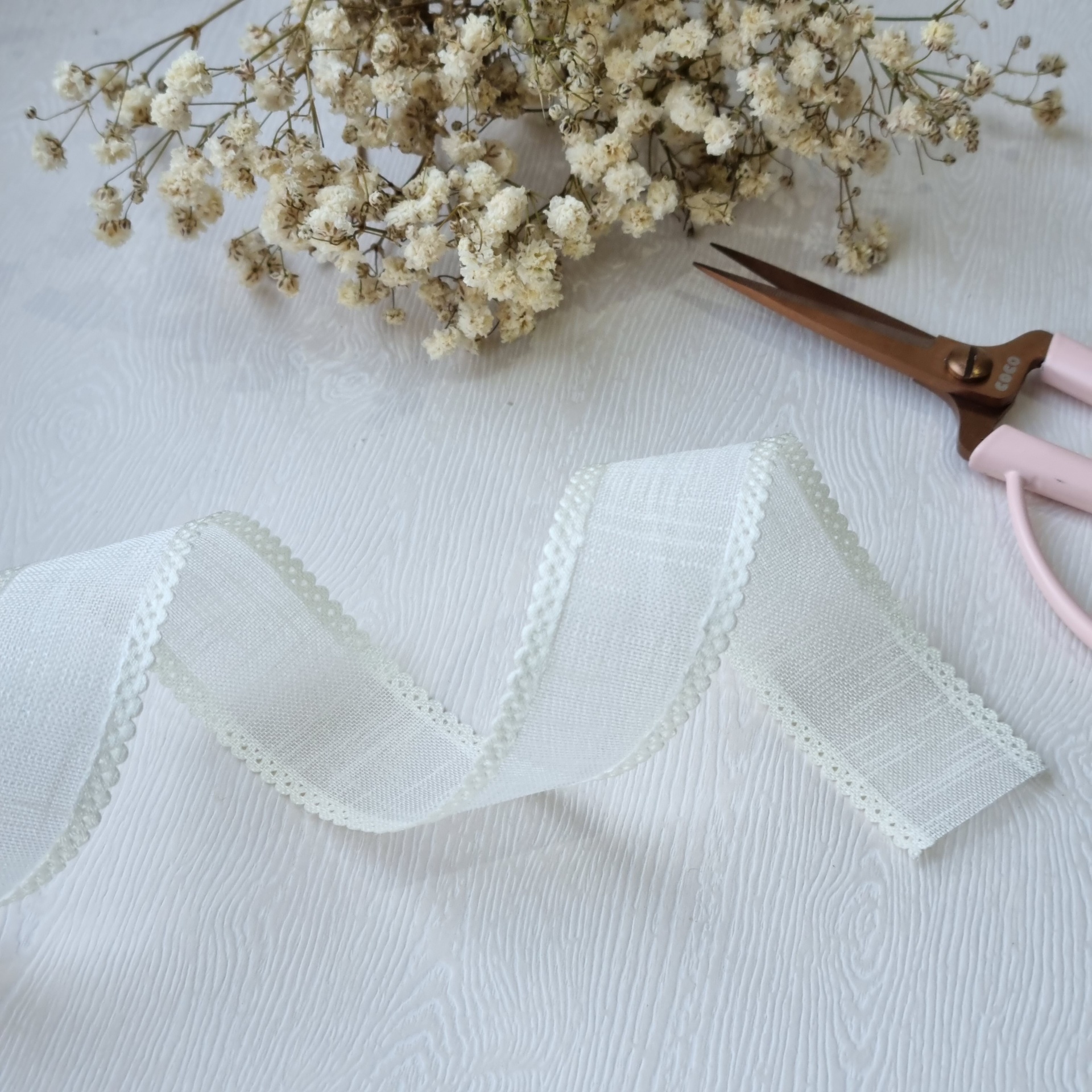 Fita branca decorativa com flores secas e tesoura rosa
