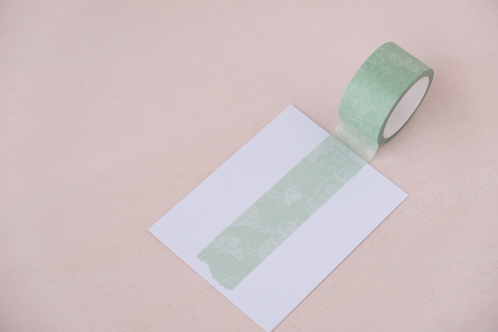 Fita adesiva verde claro com padrão decorativo sobre papel branco