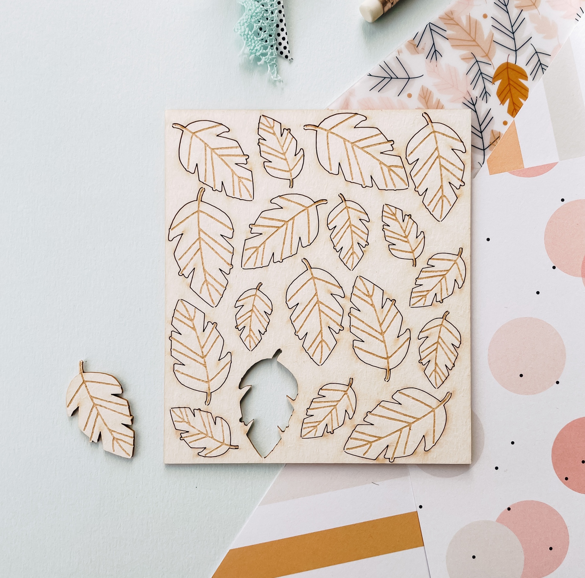 Quebra-cabeças de madeira com peças em forma de folhas sobre mesa branca com papéis decorativos