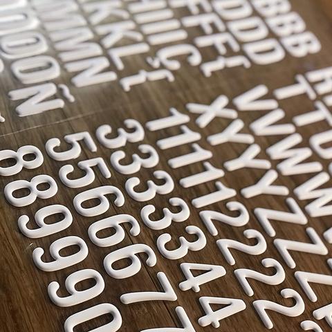 Números e letras brancos em plástico sobre superfície de madeira